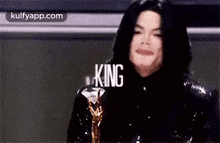 a close up of a man holding a trophy with the word king written on it .