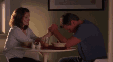 a man and a woman are sitting at a table with salt and pepper shakers on it
