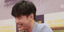 a close up of a man 's face smiling in front of a sign .