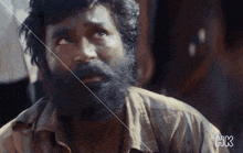a man with a beard has the letters hk on the bottom of his shirt