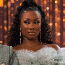a woman is wearing a ruffled top and earrings with the word netflix on the bottom right