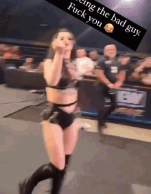 a female wrestler is giving the middle finger in front of a sign that says " being the bad guy fuck you "