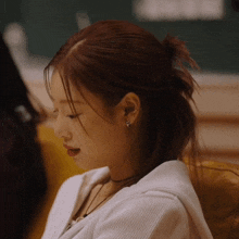 a close up of a woman 's face with her hair in a bun
