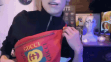a woman is holding a red gucci bag