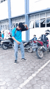 a man in a blue shirt is dancing in a parking lot with motorcycles parked in front of him