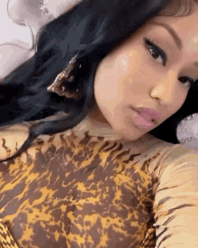 a close up of a woman wearing a leopard print top and earrings