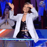 a woman in a striped jacket stands in front of a podium with the words adivina que hago on the bottom