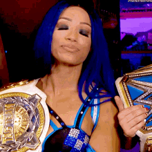 a woman with blue hair is wearing a championship belt