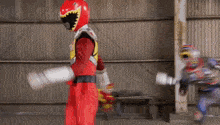 a man in a red power ranger costume is holding a sword in a warehouse .