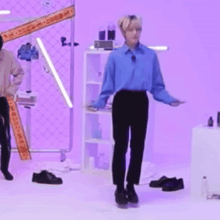 a man in a blue shirt and black pants is standing in front of a purple background .