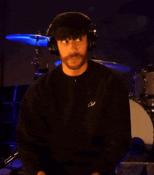 a man wearing headphones and a black shirt that says cave on it