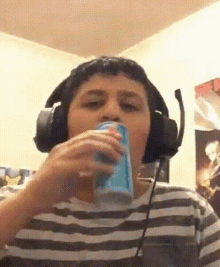 a young boy wearing headphones is drinking from a can