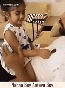 a little girl is sitting on a man 's lap and touching his arm .