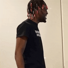 a man with dreadlocks wearing a black shirt that says ' boski ' on it