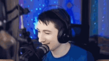 a man wearing headphones is sitting in front of a microphone and smiling .