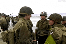 a group of soldiers are shaking hands on a beach .
