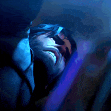 a close up of a person 's face with a purple light behind them
