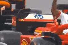 a man is standing next to a red and white race car with a hp logo on the side .