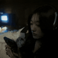 a woman wearing headphones is looking at her phone in the dark