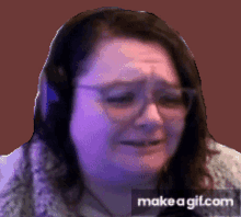 a woman wearing headphones and glasses is crying on make a gif