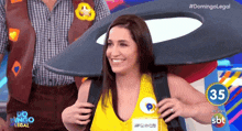 a woman in a yellow tank top is smiling in front of a screen that says domingo legal