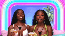 two women are sitting on a couch holding drinks