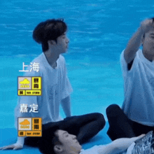 a group of young men are sitting in front of a pool with chinese writing on the screen