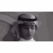 a man wearing a turban and scarf is talking in arabic .