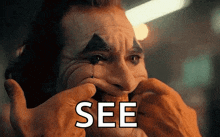 a close up of a person touching a clown 's face with the word see on it .