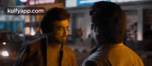 a couple of men are standing next to each other on a street at night .