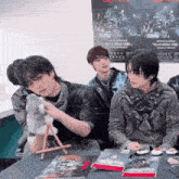 a group of young men are sitting at a table in front of a poster that says go and kill .