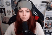 a woman wearing headphones and a headband is sitting in front of a microphone in a room .