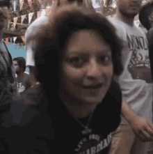 a woman wearing a shirt that says arizona is standing in a crowd of people .