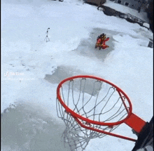 a man is jumping into a basketball hoop in the snow while holding a basketball