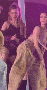 a group of women are dancing on a stage in a purple room .