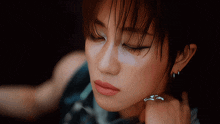 a close up of a woman 's face with earrings and a ring on her finger