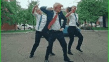 three men in suits and ties are dancing on a street
