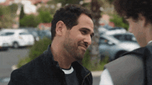 a man with a beard is smiling and talking to another man
