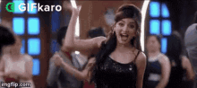 a woman in a black dress is dancing in front of a crowd of people .