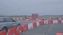 a car is driving past a red and white barrier with thinki jules written on the bottom