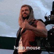 a man with long hair and a beard is giving a thumbs up and saying hello mouse