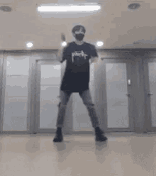 a man is dancing in a room with a mask on his face .