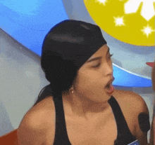 a woman wearing a black tank top and a black headband with her tongue out