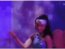 a woman in a blue dress is dancing in front of a purple background