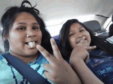 two girls in a car one wearing a shirt that says " the out "