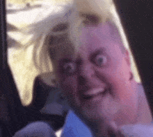 a woman in a car making a funny face with her hair blowing in the wind