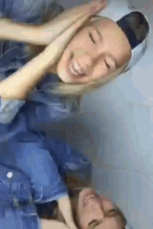 a couple of girls are laughing and one is wearing a hat