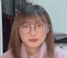 a girl wearing glasses and a pink sweater is making a funny face .