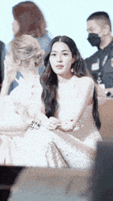 a woman in a white dress is sitting in front of a crowd