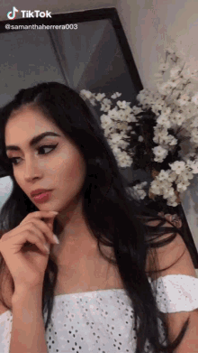 a woman in a white off the shoulder top has a tiktok watermark on her face